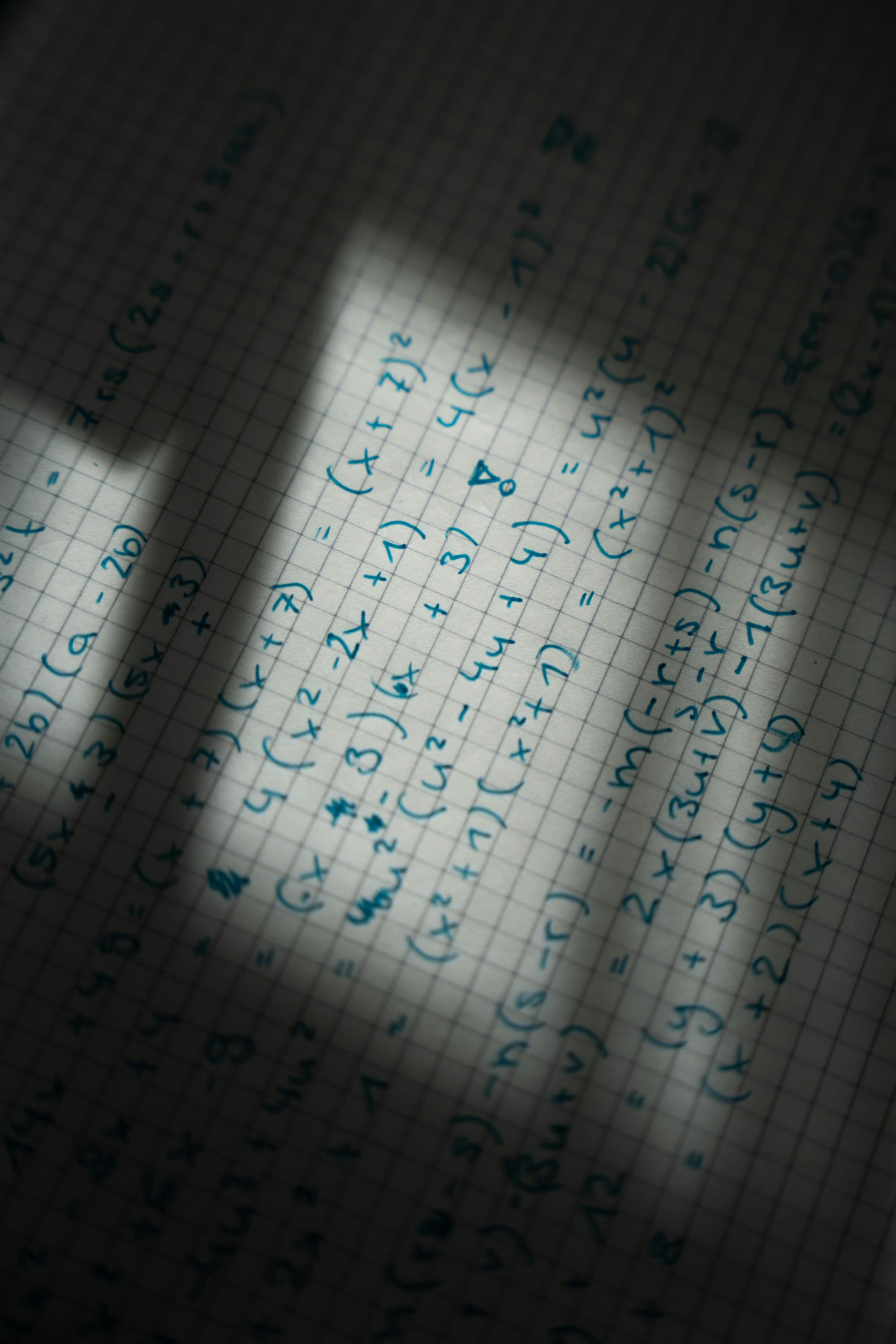 Graph paper with handwritten equations, seen in shadow