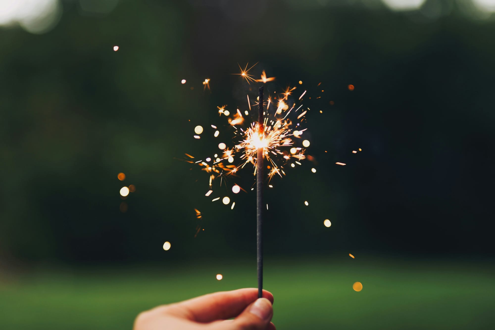 A hand holding a lit sparkler
