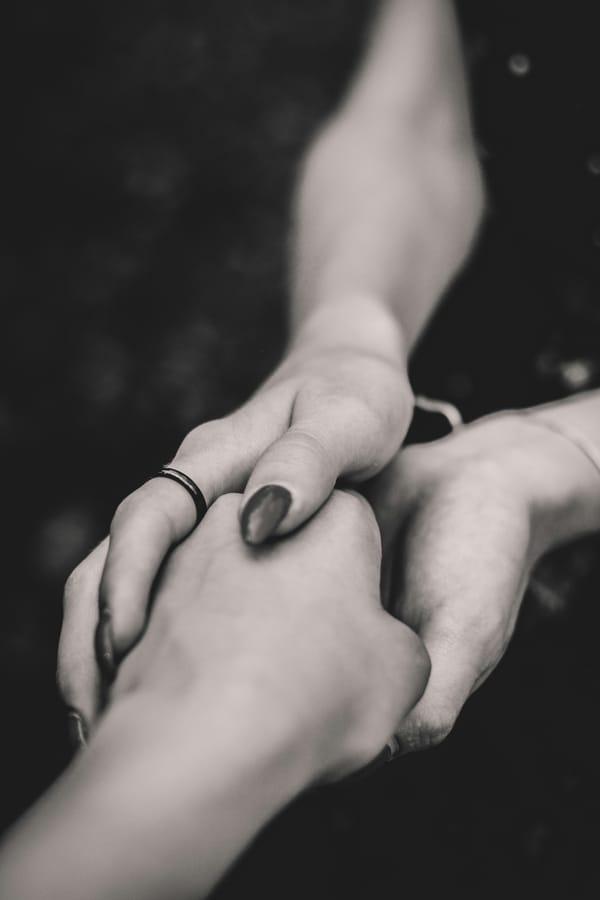Close-up of two hands holding another in a moment of connection, in black and white