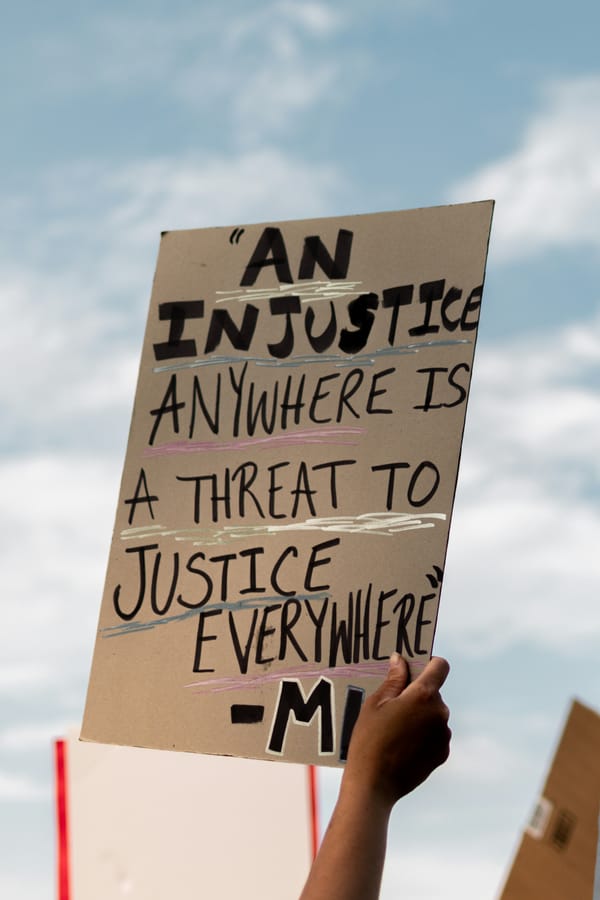 A handwritten protest sign, with the MLK quote "An injustice anywhere is a threat to justice everywhere"