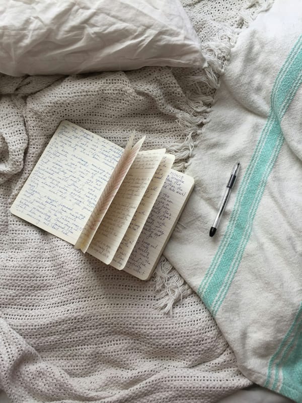 Writing journal and pen spread out over blankets