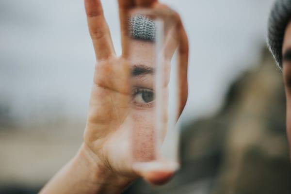 A fragmented face and singular eye as seen in a mirror