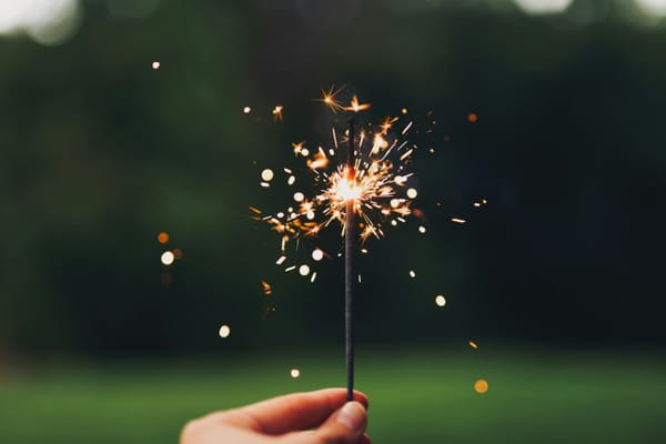 A hand holding a lit sparkler